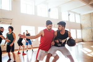 Men playing basketball in a gym.
